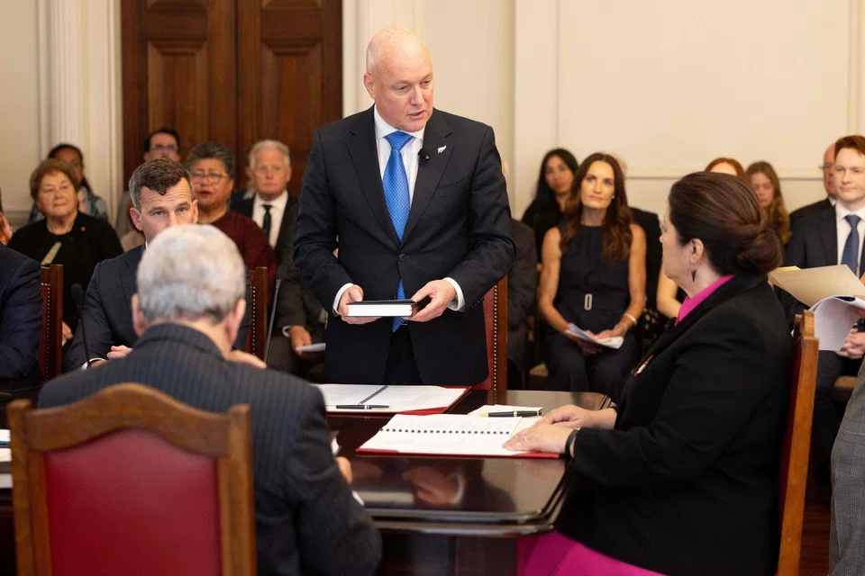 New Zealand's new Prime Minister Christopher Luxon (C) takes an oath before New Zealand's Governor General Dame Cindy Kiro (R) during the swearing-in of the new government at Government House in Wellington on Nov 27, 2023. 