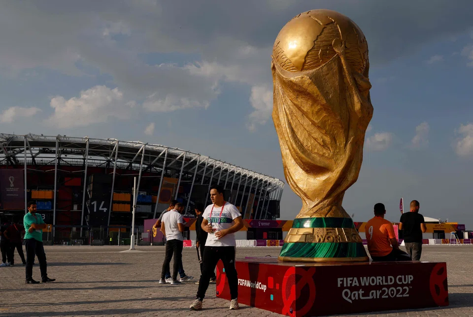 People pose for photos next to a giant replica on the World Cup trophy in front of Stadium 974 on Nov 18, 2022 in Doha, Qatar, ahead of the Qatar 2022 World Cup.