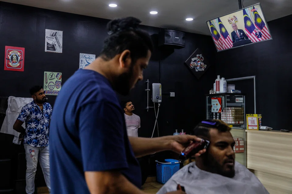 Customers in a barber shop in Dengkil, Selangor, watch a live broadcast of the announcement by Malaysian Prime Minister Ismail Sabri Yaakob on the dissolution of parliament and the impending general election.  