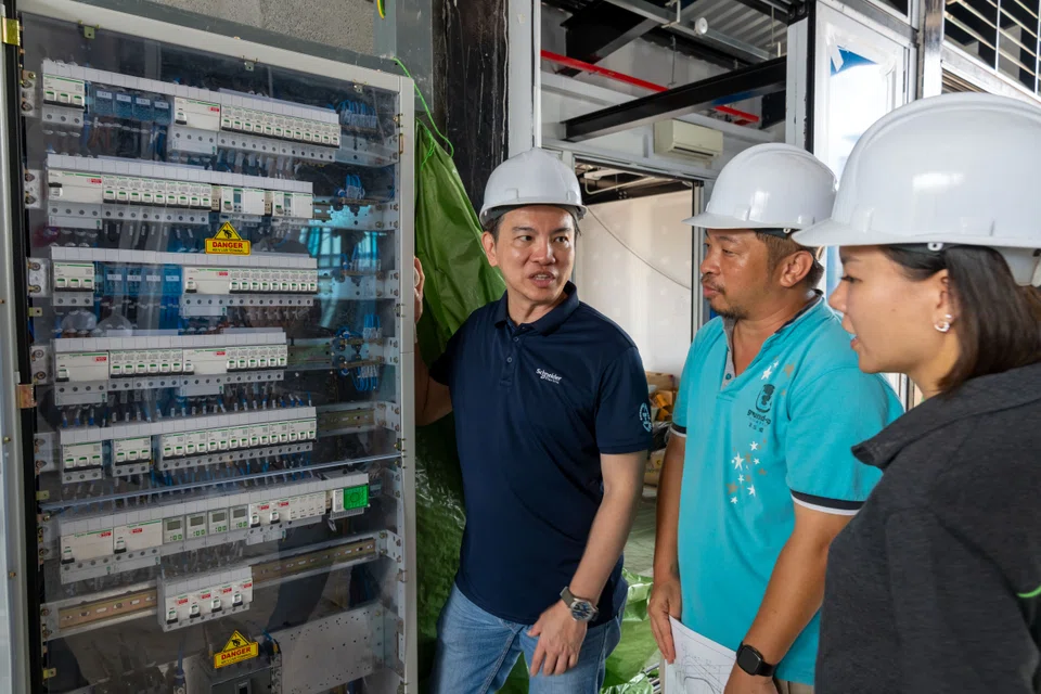 Jackson Seng (left), vice-president of digital energy division for East Asia region at Schneider Electric, and Cai Bingyu (centre), executive director of GUI, in front of one of Schneider's sponsored appliances at Kampung Kampus.