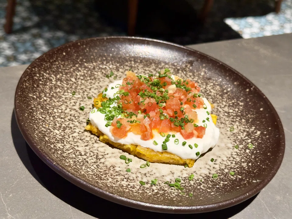 Green plantain pancakes topped with tomatoes and stracciatella cheese.