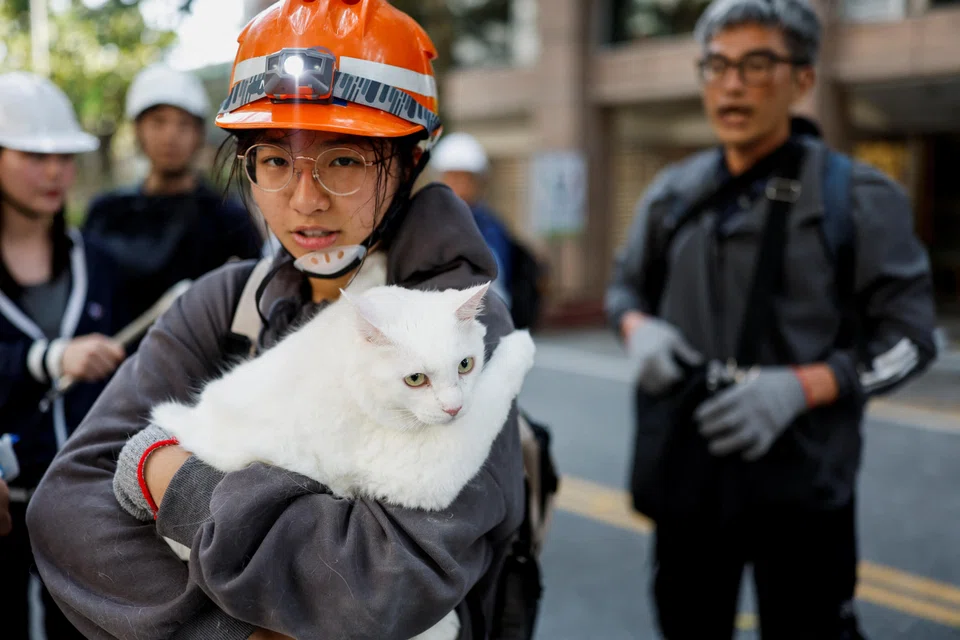 Katie Huang, 16, carries her cat Tako, who she found hiding behind a bed while collecting belongings with her family from a damaged building, following the earthquake, in Hualien, Taiwan.