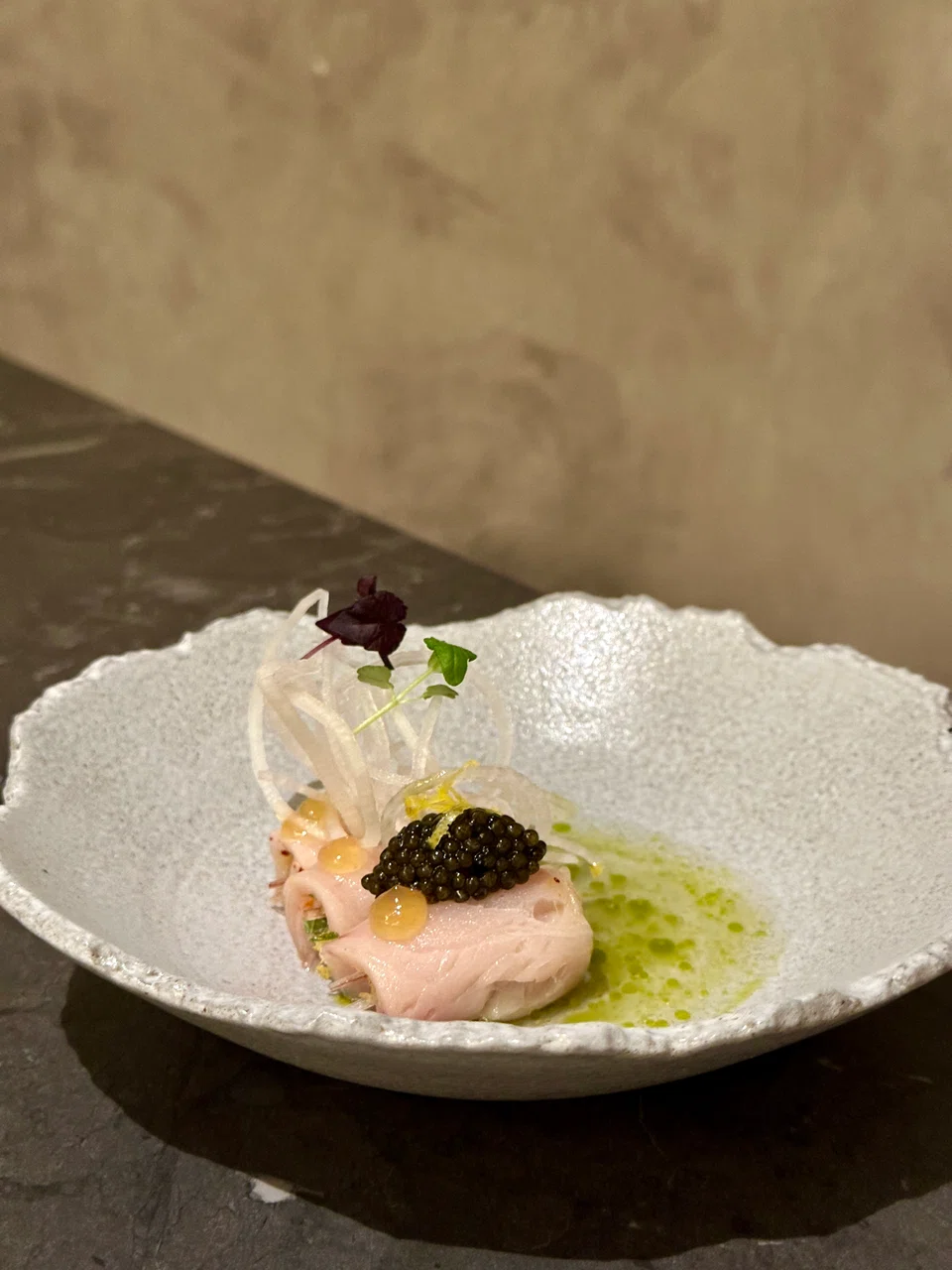 Rolled hamachi slices topped with caviar in tomato water.