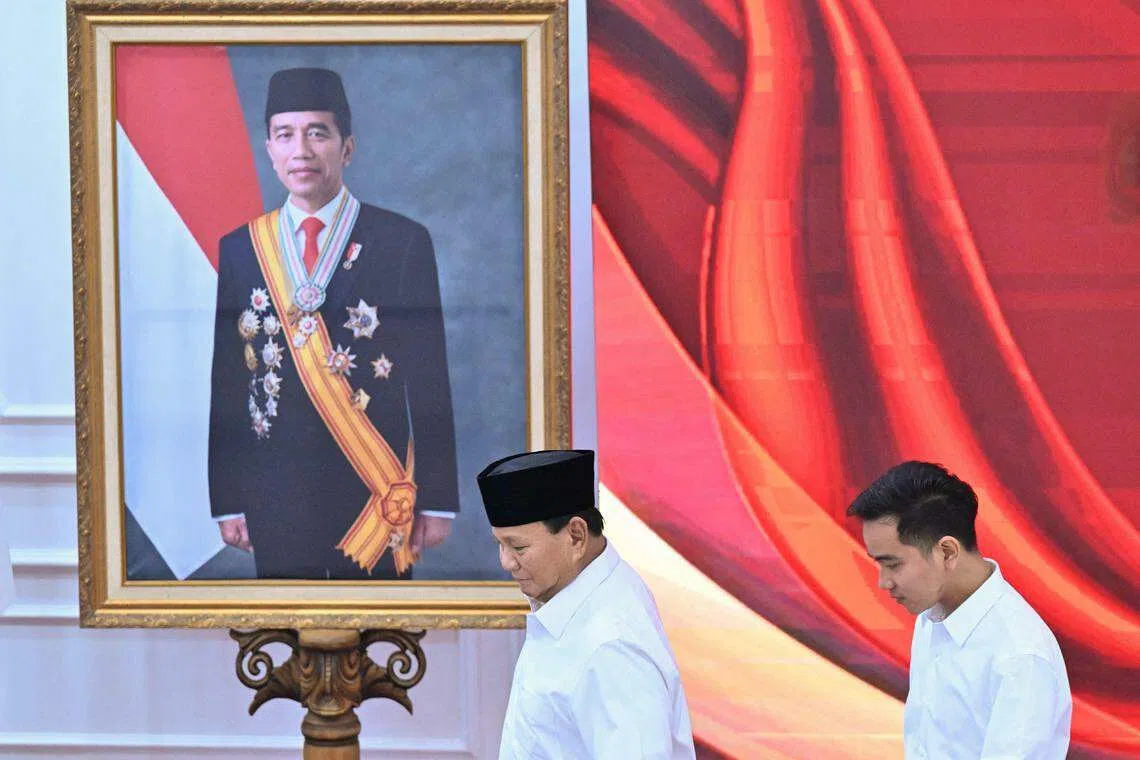 Indonesian President-elect Prabowo Subianto (left) and Vice-President-elect Gibran Rakabuming Raka walk past a picture of Gibran's father, President Joko Widodo, at an event in Jakarta on Apr 24.