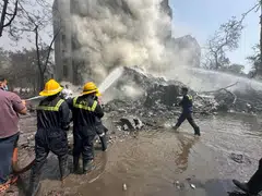 Firefighters working as smoke rises at the site where an Air India plane crashed in Ahmedabad, India.