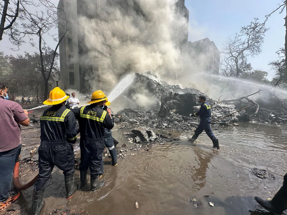 Firefighters working as smoke rises at the site where an Air India plane crashed in Ahmedabad, India.