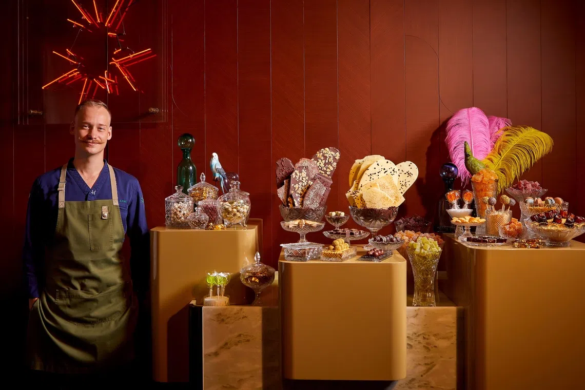 Head chef Arne Riehn poses beside IGNIV's star attraction: a candy "store" of assorted pralines, caneles and candy.