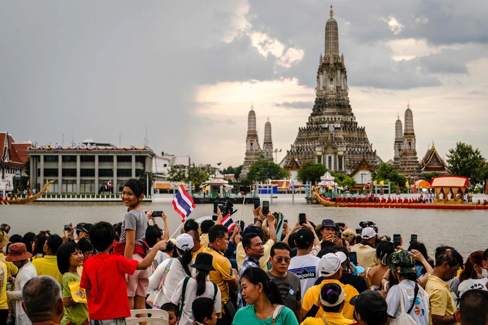 Spectators watch a procession along the Chao Phraya River in front of Wat Arun in Bangkok. Singapore consumers are spending the most in Thailand and Malaysia, says UOB. 