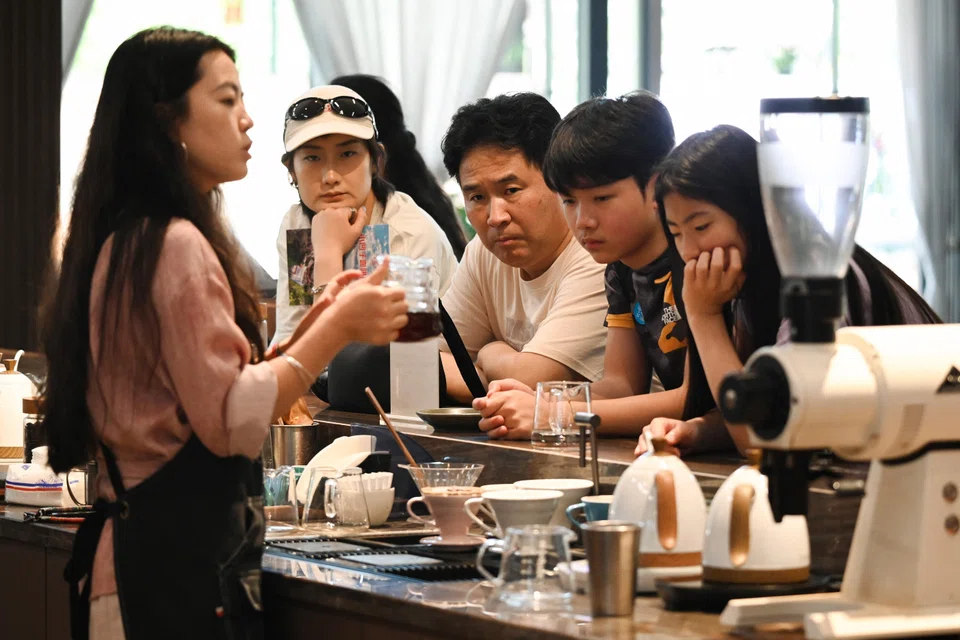 Clusters of tourists sipping boutique brews in an airy cafe while overlooking the verdant slopes of Xiaowazi, or Little Hollow, coffee plantation.