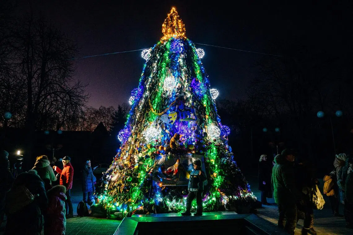 A Christmas tree made of camouflage nets draws a small crowd in Mykolaiv, Ukraine, on Dec 19, 2022, amid the Russian invasion.