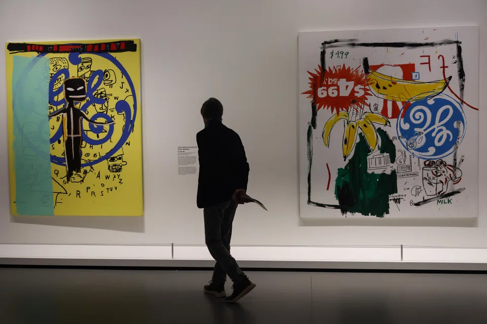A visitor looks at 'EG, 1984-1985' (L) and 'Bananas, 1985' by American artists Jean-Michel Basquiat and Andy Warhol on display at the 'Basquiat x Warhol' exhibition at the Louis Vuitton Foundation in Paris, France, April 4, 2023. The exhibition runs from Apr 5 to Aug 28, 2023.  