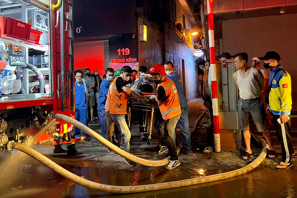 Fire and rescue workers aid a victim to an ambulance following a big fire at an apartment block in Hanoi, Vietnam on May 24, 2024.
