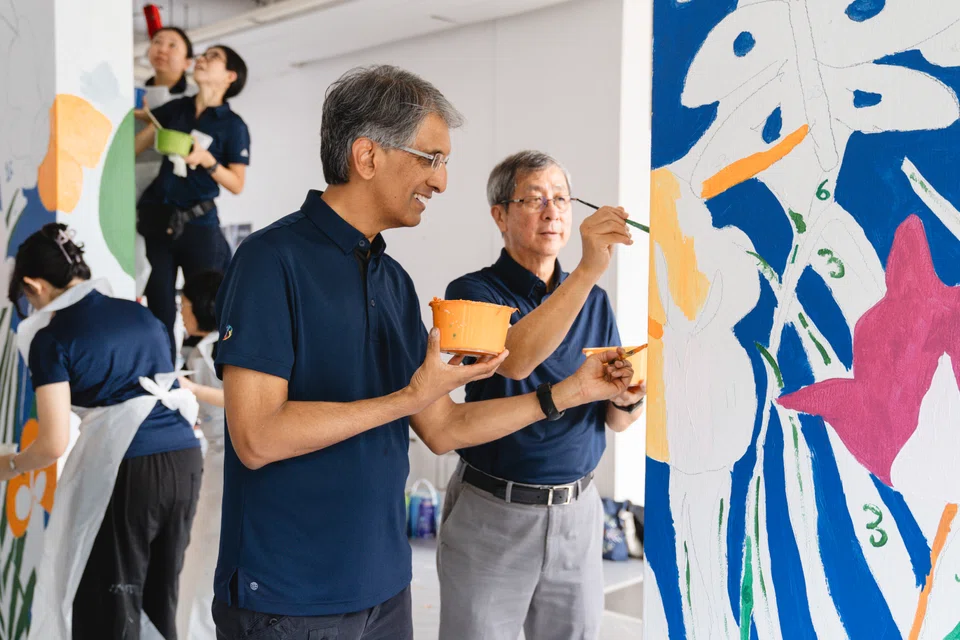 Temasek's chief executive Dilhan Pillay (left) and chairman Lim Boon Heng helping to paint a mural in an HDB void deck as part of Temasek's Community Day activities.
