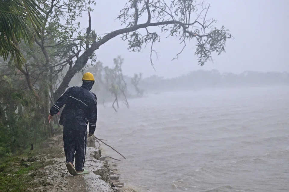 A volunteer walks on a damaged embankment along the Sonatola river during heavy rainfall in Patuakhali on May 27, 2024, following the landfall of Cyclone Remal in Bangladesh.