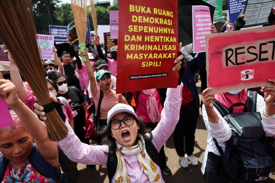 Women shout slogans during a protest against lawmakers' perks and police brutality, brandishing brooms as a symbol of their calls for reform.
