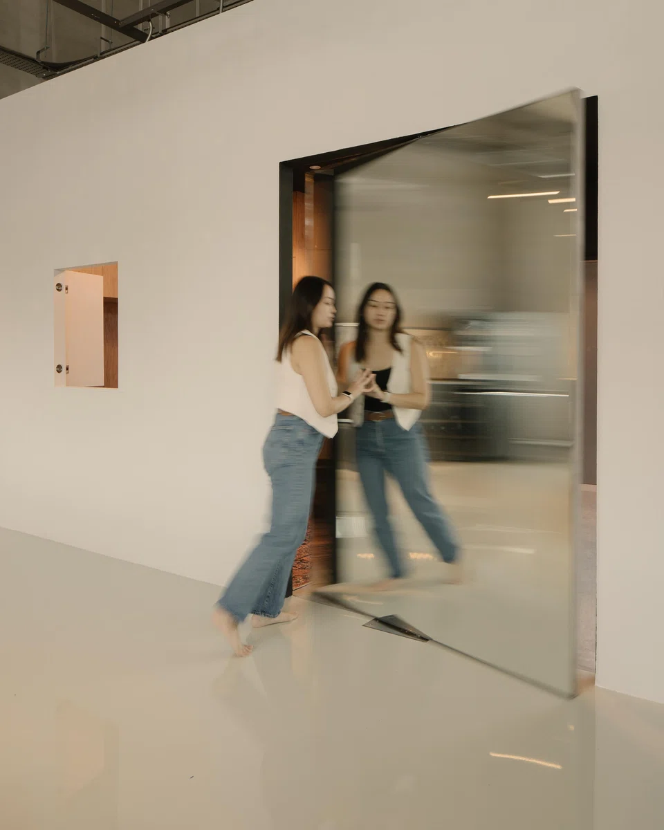 A mirror-clad swivel door separates the meeting room and the workspace.