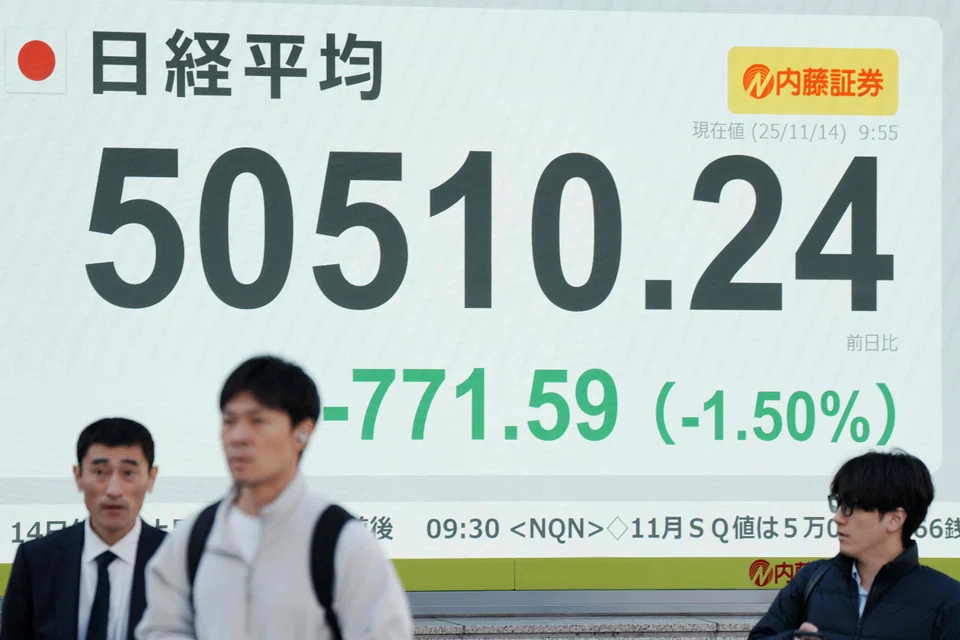 Pedestrians walk past an electronic quotation board displaying numbers of the Nikkei Stock Average on the Tokyo Stock Exchange in Tokyo, Japan, Nov 14, 2025. 