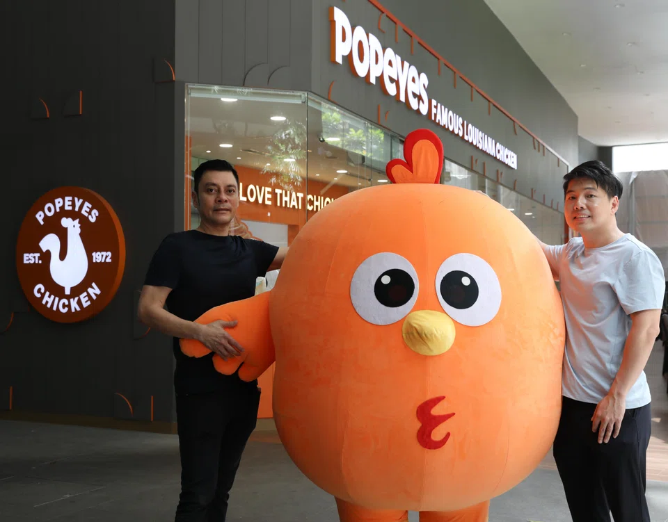 Tan Kim Siong, founder and chairman of Fei Siong Group (left), with Jedrick Tan, chief strategy officer of Fei Siong, at the Popeyes Singapore outlet in Somerset.