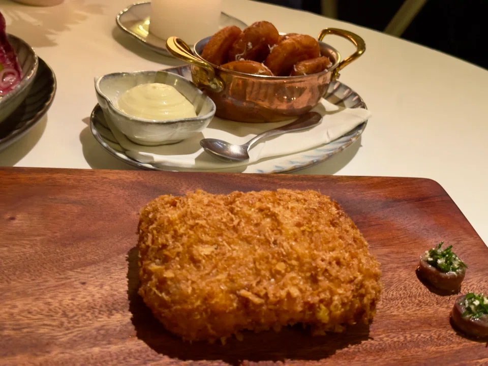Breaded veal cutlets stuffed with ham and cheese are deep-fried and served with pommes dauphine.