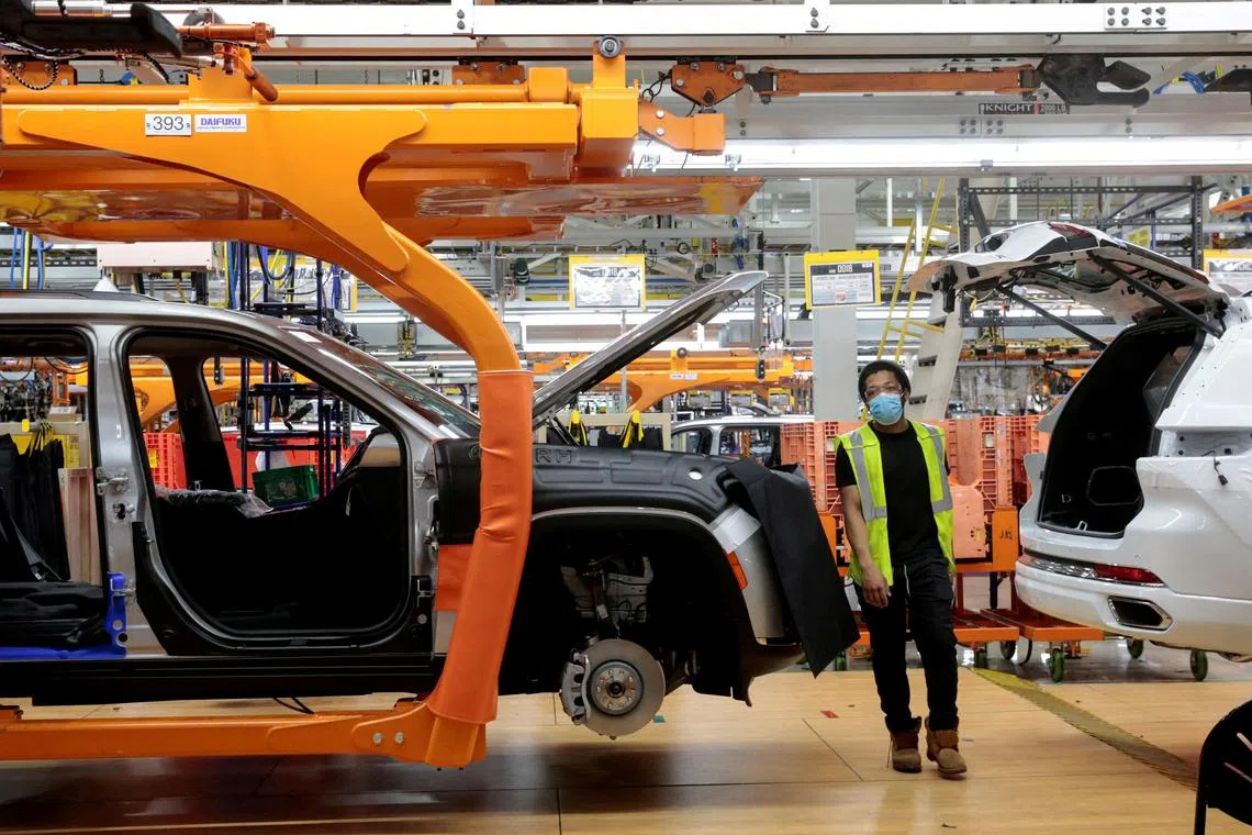 FILE PHOTO: A Stellantis assembly worker walks between two 2021 Jeep Grand Cherokee L vehicles on the assembly line at the Detroit Assembly Complex - Mack Plant in Detroit, Michigan, U.S., June 10, 2021. REUTERS/Rebecca Cook/File Photo