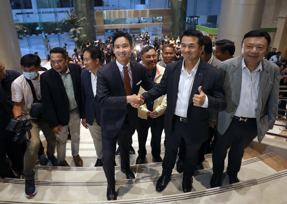 Move Forward Party's leader and its prime ministerial candidate Pita Limjaroenrat (centre) shake hands with Pheu Thai Party leader Cholnan Srikaew as the eight-party coalition reaffirmed its backing for Pita to become prime minister.