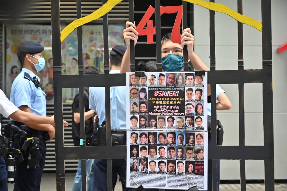 A protester stands behind a mock jail with photos of the 47 pro-democracy figures already in prison, Sept 19, 2021.