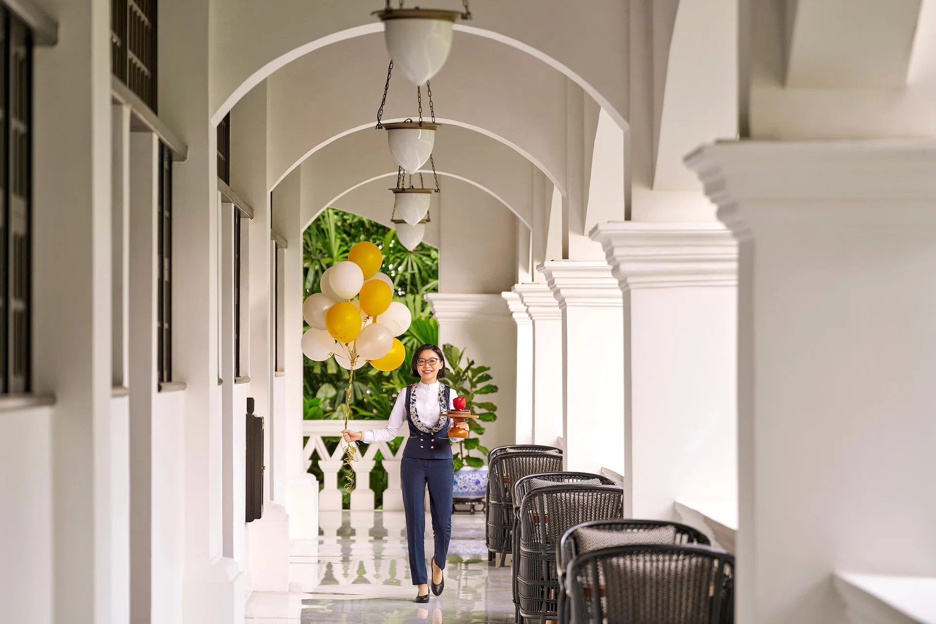 Exterior view of Raffles Hotel Singapore, a white colonial-style building with lush greenery.