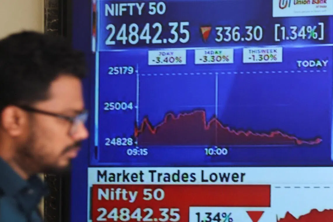 A man walks past a screen displaying stock market updates at the Bombay Stock Exchange (BSE) in Mumbai, India, March 2, 2026. 