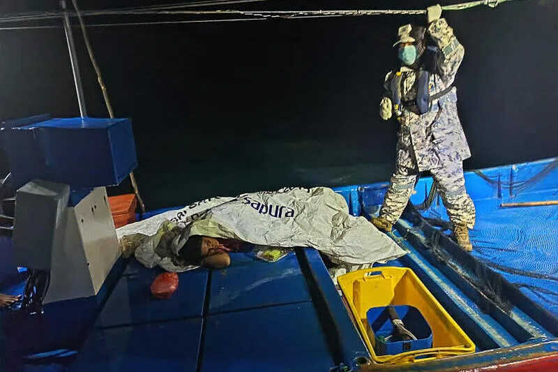 Malaysian Maritime Enforcement Agency staff member checking on a survivor rescued by a fishing boat during a search and rescue operation off the coast of Langkawi.