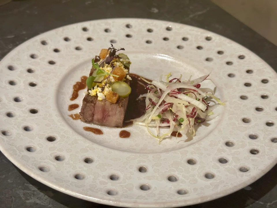 Sous vide tongue is topped with crumbled egg and croutons.