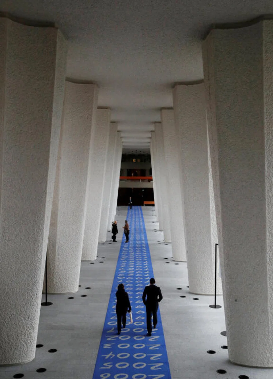 People walking along a corridor of the Governing Body at the ILO in Geneva. The job losses follow the US administration’s decision to reduce voluntary contributions.
