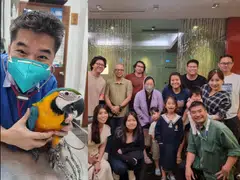 Dr Kenneth Tong with one of his avian patients; the staff of AAVC and some of their families.