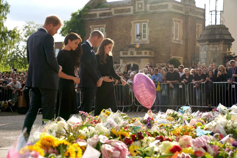 From left: Britain's Prince Harry, Duke of Sussex, his wife Meghan, Duchess of Sussex, Britain's Prince William, Prince of Wales and his wife Catherine, Princess of Wales, look at floral tributes laid by members of the public on the Long walk at Windsor Castle on Sep 10 (Saturday)  before meeting well-wishers.  Commentators said it was a show of unity that suggested that the death of the monarch could lead to a rapprochement.