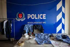 A room set up to imitate a Singapore police station, including fake Singapore police uniforms, inside a compound in O'Smach used for scam operations.