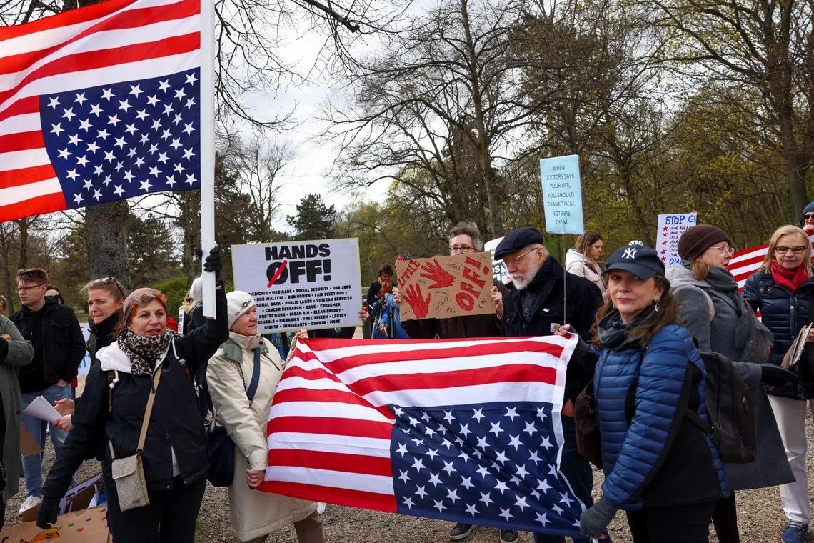 Demonstrators hold US flags upside-down during a protest against US President Donald Trump on Apr 5 in Berlin.