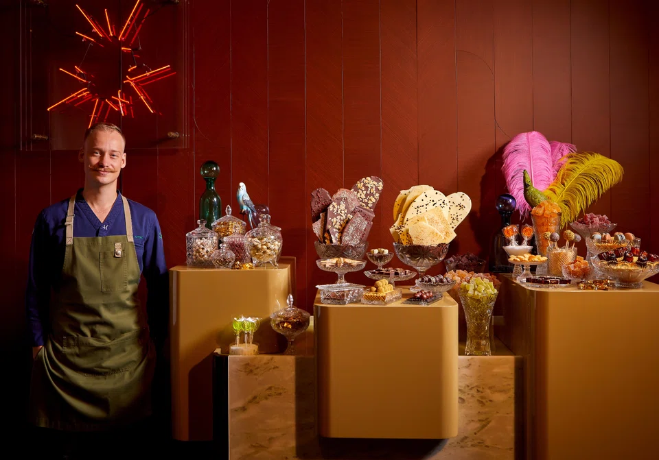 Head chef Arne Riehn poses beside IGNIV's star attraction: a candy "store" of assorted pralines, caneles and candy.