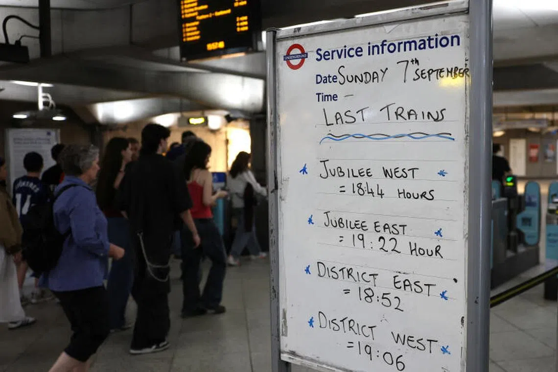 Travellers walk past a passenger information sign ahead of planned tube rail strikes, at Westminster Underground Station in London.