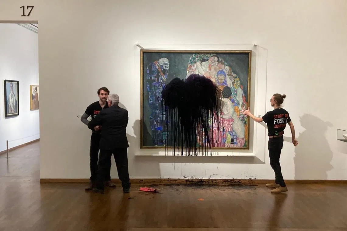 Florian Wagner, of the Last Generation group, is restrained while a fellow activist has glued himself to the painting Death and Life by Gustav Klimt after pouring black liquid over it, at the Leopold Museum in Vienna, Austria on Nov 15.