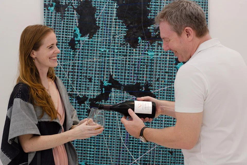  Brad Brown (right), co-founder of Sakesho, pouring sake for a gallery visitor. The Business Times is partnering Sakesho and Singapore Gallery Month for an art and sake appreciation event.