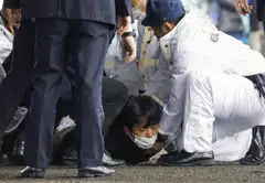 NHK footage show crowds running away as several police officers appear to pin a man to the ground before removing him from the scene