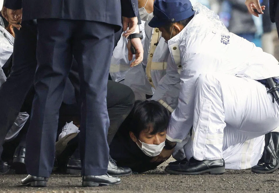 NHK footage show crowds running away as several police officers appear to pin a man to the ground before removing him from the scene