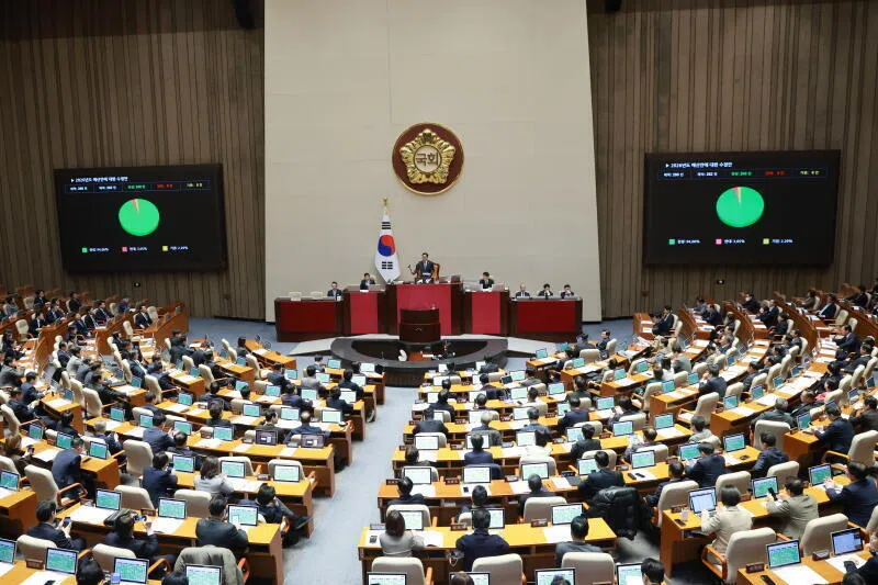 Lawmakers of the ruling and opposition parties pass the government's 2026 budget of 727.9 trillion won that calls for more spending to prop up the economy and on national defence during a plenary session at the National Assembly in Seoul