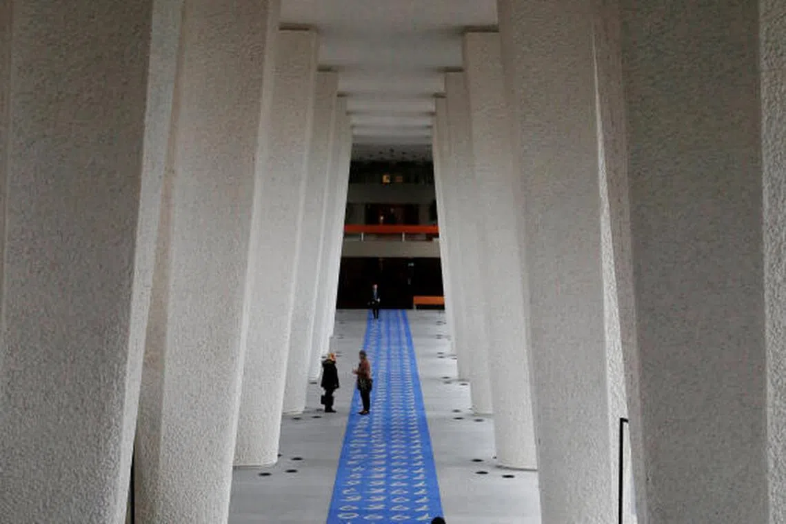 People walking along a corridor of the Governing Body at the ILO in Geneva. The job losses follow the US administration’s decision to reduce voluntary contributions.