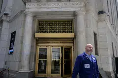 A trader walks out of the New York Stock Exchange on Wall Street in New York. Some Wall Street firms are revising their profit projections for multiple S&P 500 industry groups, based on the adoption of AI.