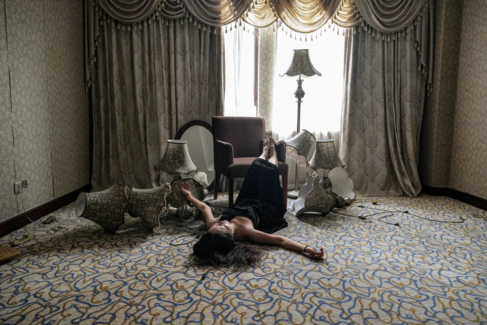 Model Mao Yi posing for pictures as she lies on the ground at a room inside an abandoned hotel in Shanghai.  