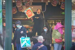 A staff member advertises clothing at the main shopping area in Shanghai, China, March 14, 2023. A lingering sense of caution about the sustainability of China's rebound points to a potentially rocky year ahead. 