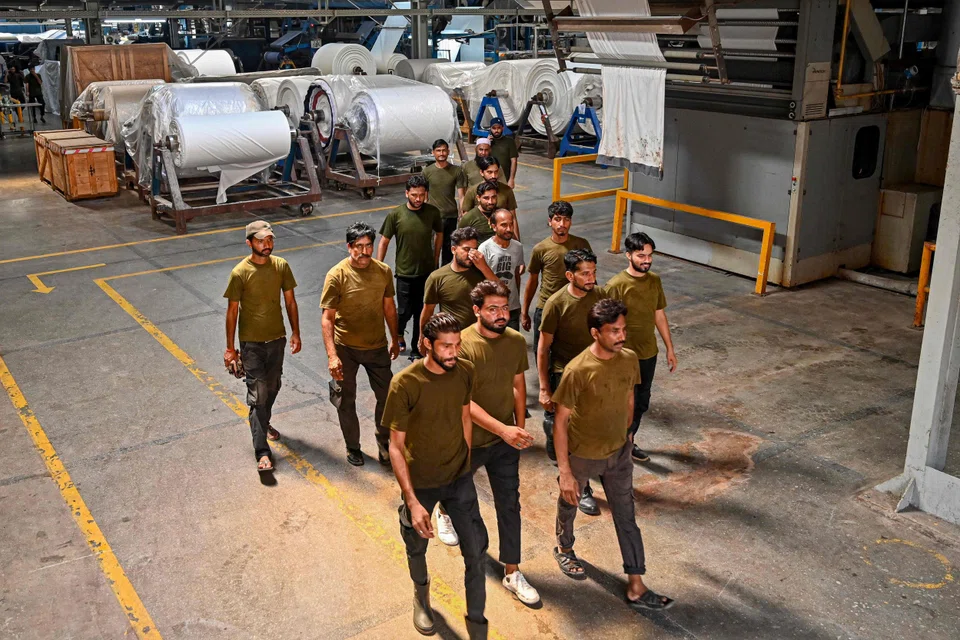 Textile workers leave after a workday at Kohinoor Mills in Lahore, Jul 30, 2023. Pakistan's industrial manufacturing sector – like elsewhere in the world – has suffered from the slowdown in global consumption and the rise in energy costs following the outbreak of war in Ukraine. 