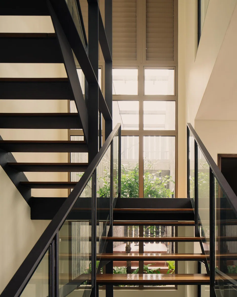 Large glass panels open up the staircase to views of the courtyard by the party wall. 