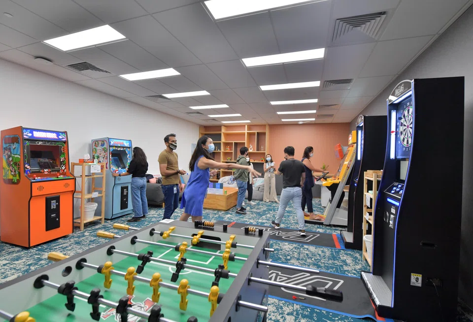 Meta employees making use of the games-room facilities in the company's Singapore office in May 2022.  Employers now routinely offer their staff perks such as free food, gym membership and flu  jabs. 