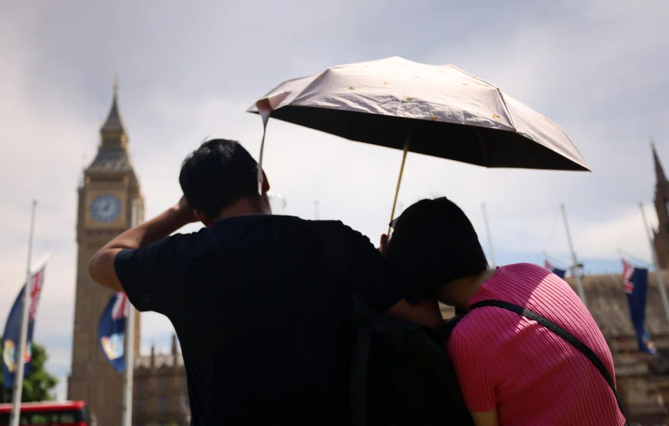 A couple shelters from the sun under an umbrella in London, Britain, July 1, 2025. 